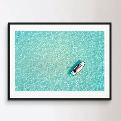 Aerial view of a woman on a surfboard in the turquoise waters