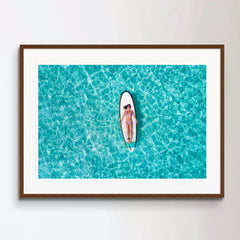 Woman in bikini is sunbathing on a surfboard