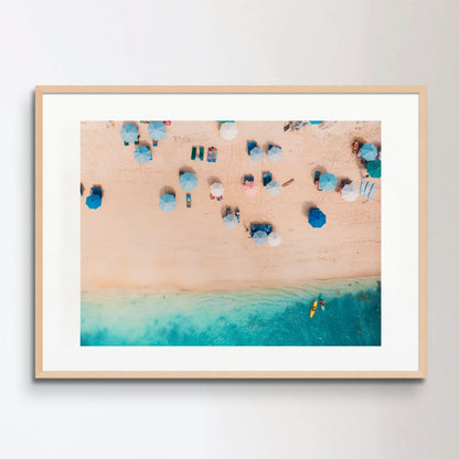 Top view of sandy beach with turquoise sea water and colorful blue umbrellas, aerial drone shot