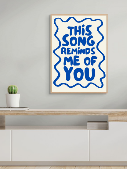 Aesthetic wall art print saying 'This song reminds me of you' framed on a modern shelf.