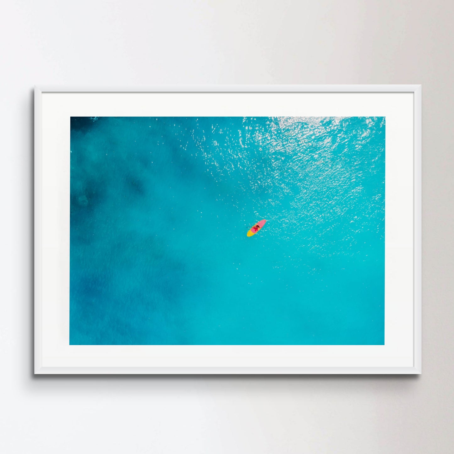 Aerial view of woman on stand up paddle board in blue ocean.