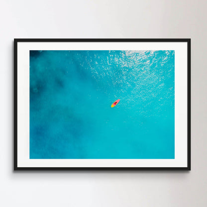 Aerial view of woman on stand up paddle board in blue ocean.