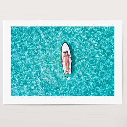 Woman in bikini is sunbathing on a surfboard