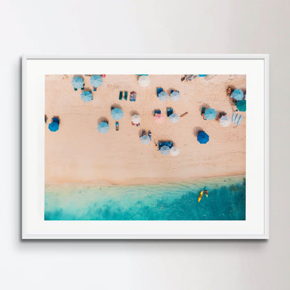 Top view of sandy beach with turquoise sea water and colorful blue umbrellas, aerial drone shot