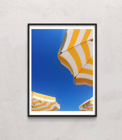 Bottom view of a yellow and white sunbrella on the beach or near a pool