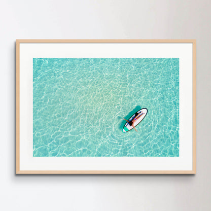 Aerial view of a woman on a surfboard in the turquoise waters