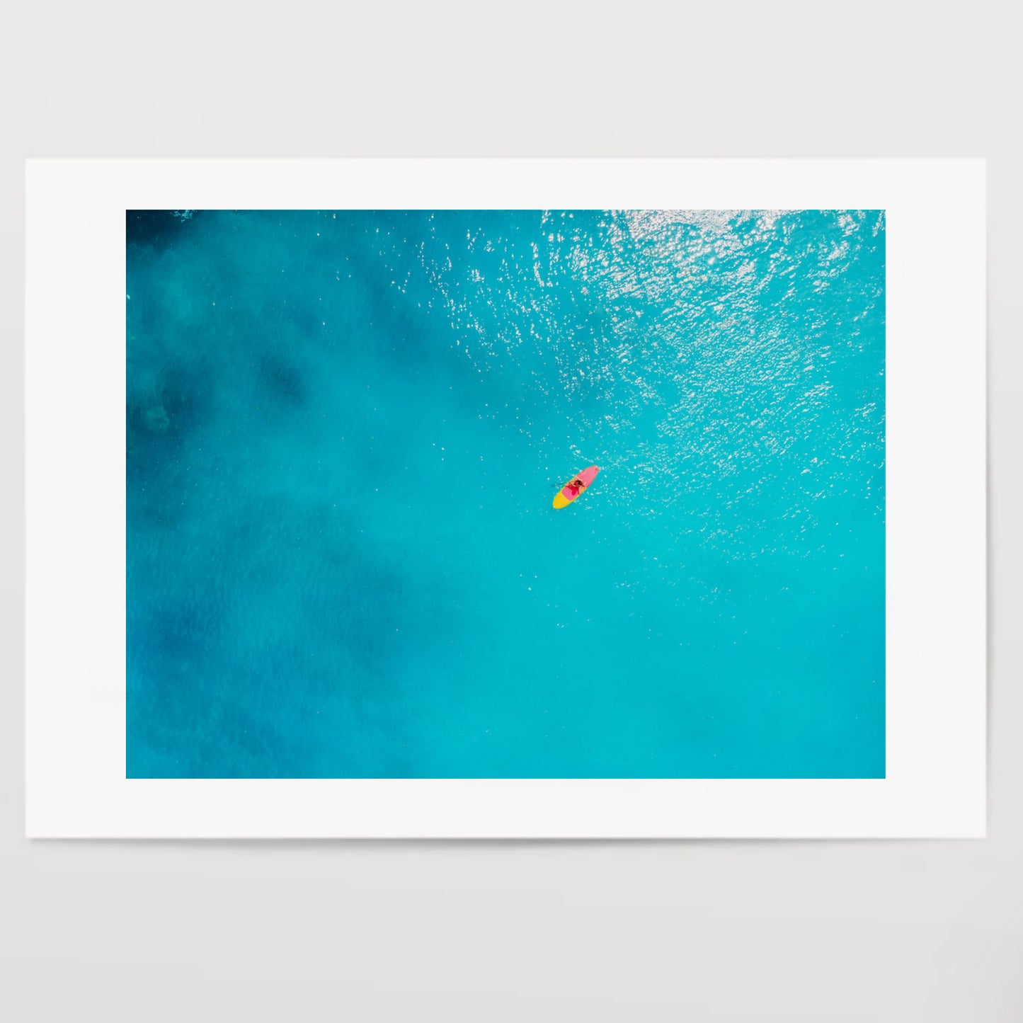 Aerial view of woman on stand up paddle board in blue ocean.