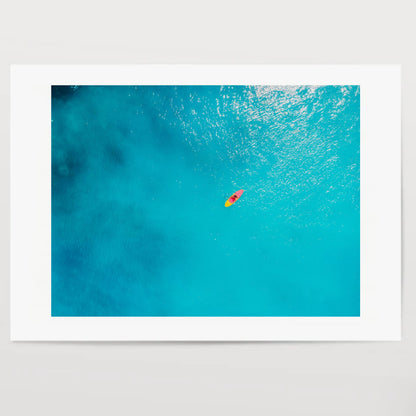 Aerial view of woman on stand up paddle board in blue ocean.