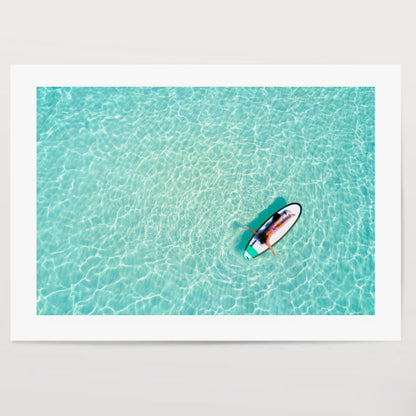 Aerial view of a woman on a surfboard in the turquoise waters