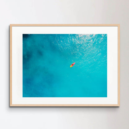 Aerial view of woman on stand up paddle board in blue ocean.