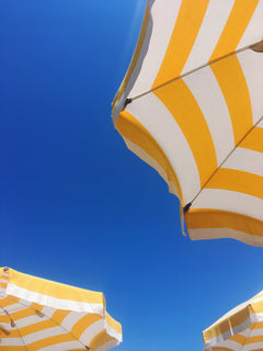 Bottom view of a yellow and white sunbrella on the beach or near a pool
